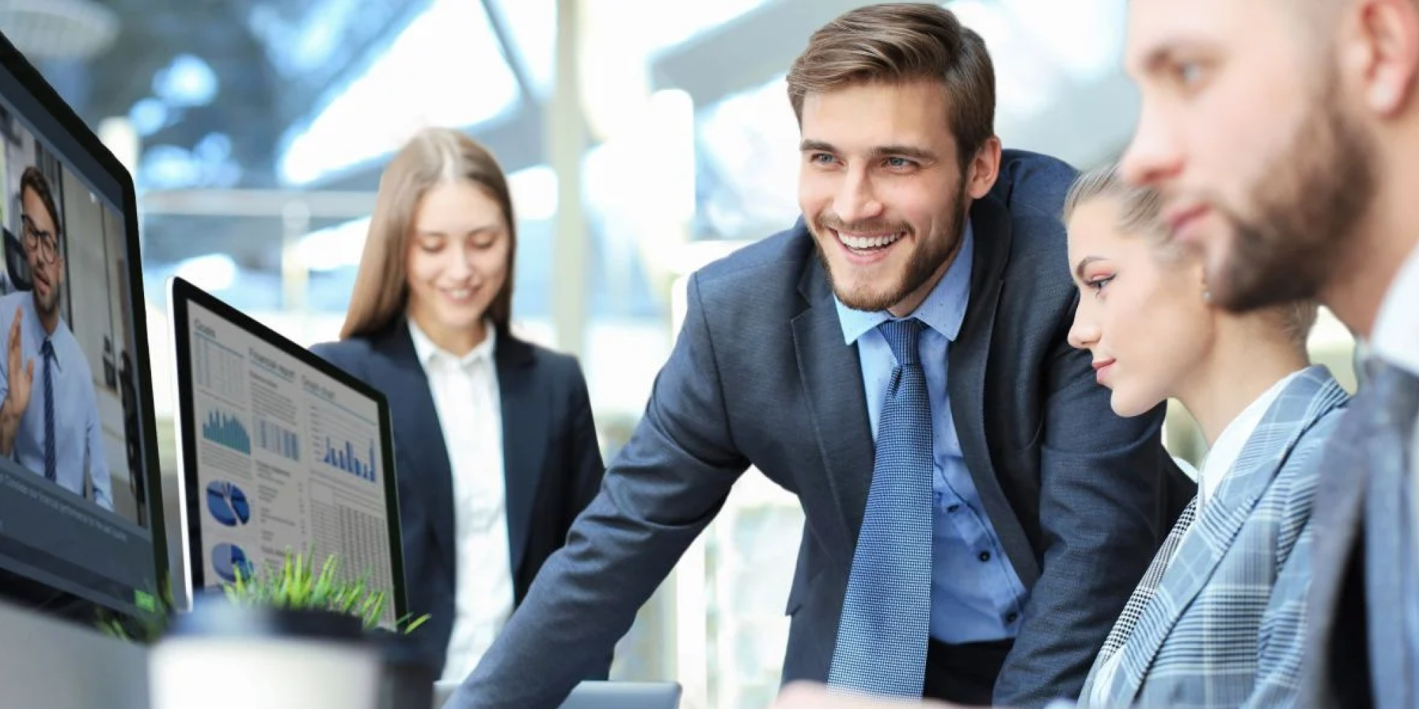 equipe de tecnologia reunida enquanto CTO analisa sorrindo gráficos de um computador