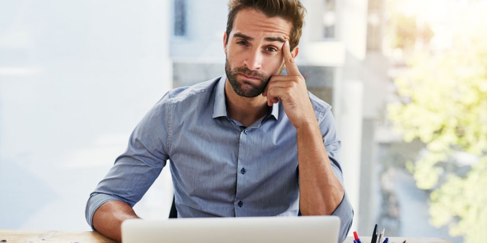 CTO com expressão cansada diante do computador, representando a sobrecarga emocional e mental comum em lideranças tech