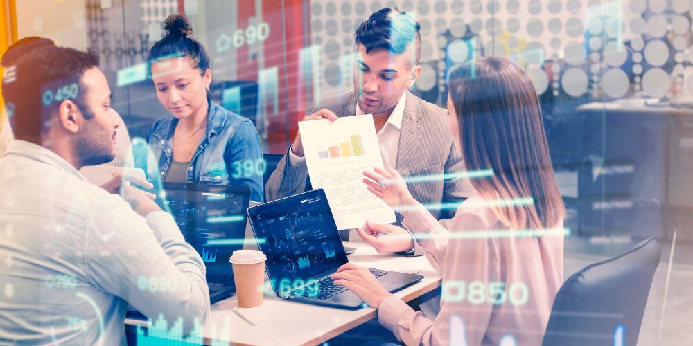 Quatro profissionais em um escritório moderno analisam um gráfico de barras impresso enquanto números e indicadores financeiros digitais aparecem sobrepostos, simbolizando decisões guiadas por dados.