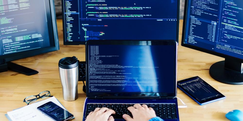 Pessoa programando em ambiente com múltiplas telas, representando o uso de IA para automação no desenvolvimento de software.