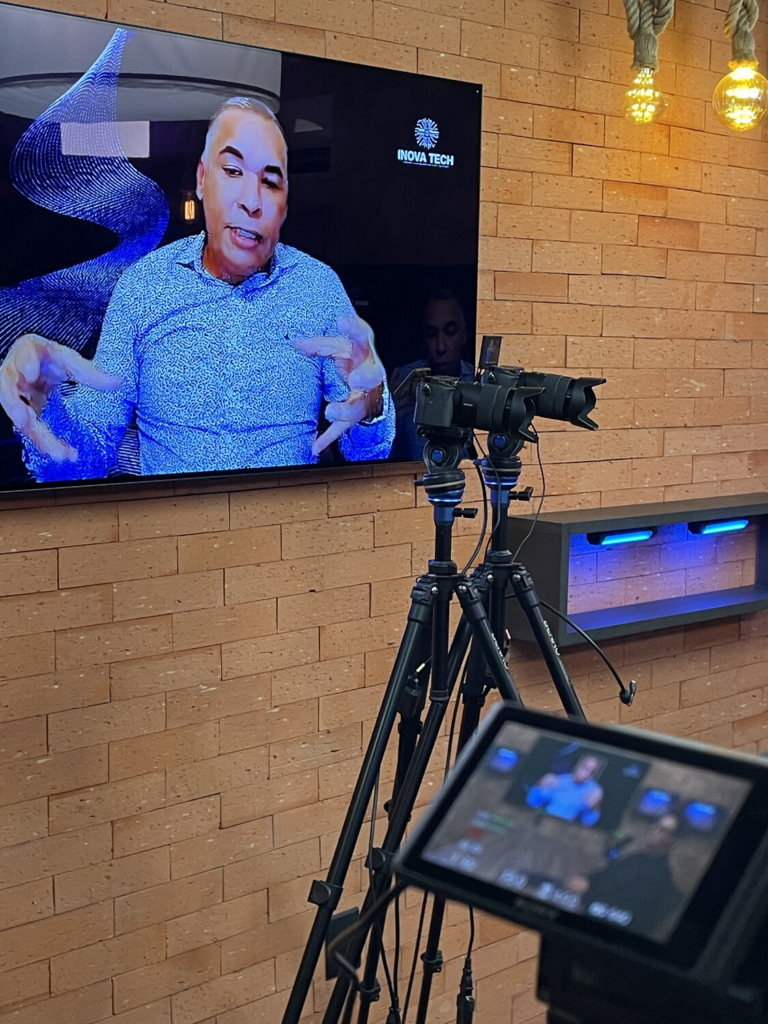 Bastidores da gravação do Vibbracast, com câmeras posicionadas diante da tela enquanto Joás Andrade participa remotamente do episódio.