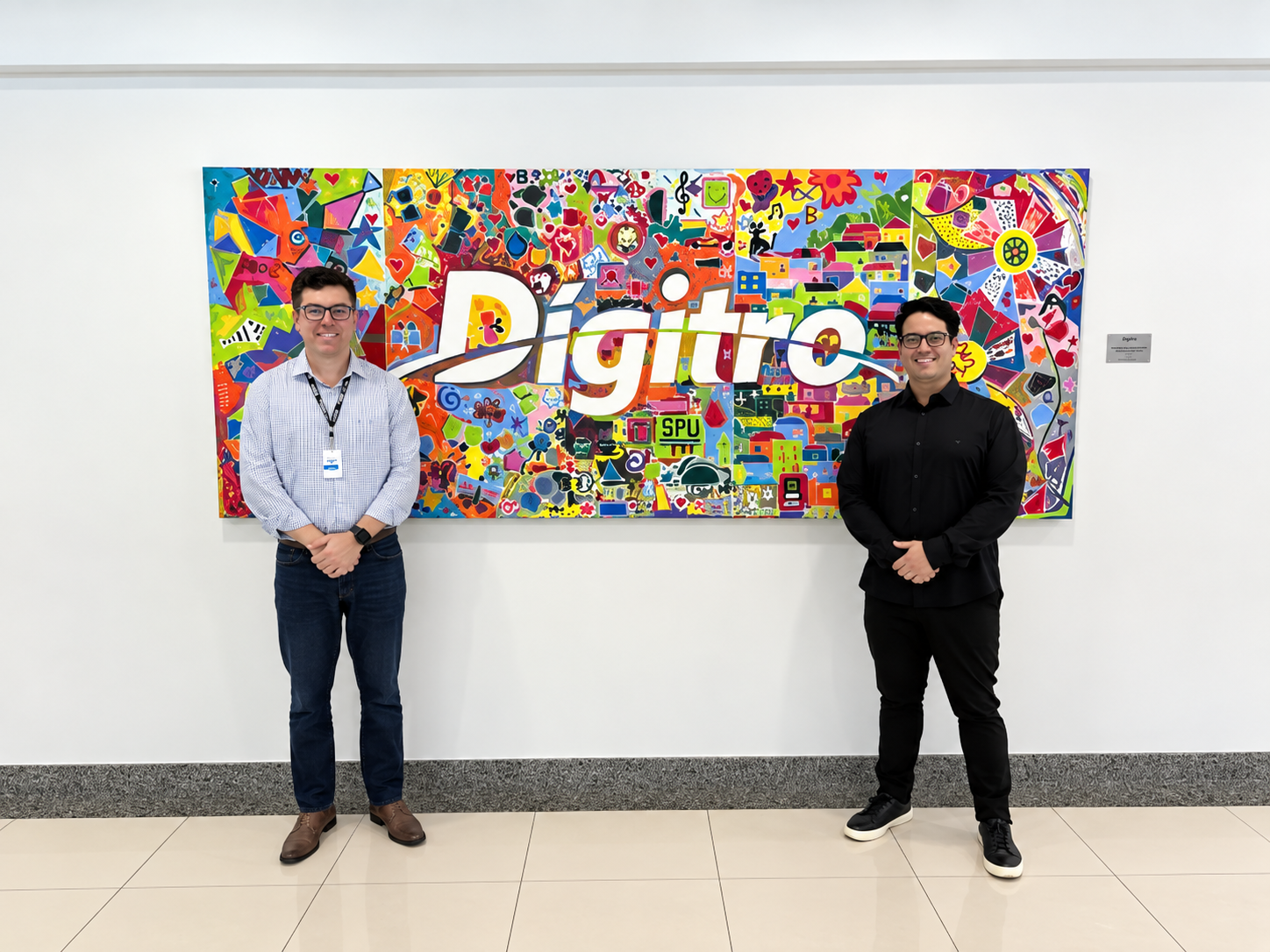 Agenor Pacheco, Diretor de Tecnologia da Digitro, e o Leandro Oliveira posando em foto na frente do logo da Digitro.